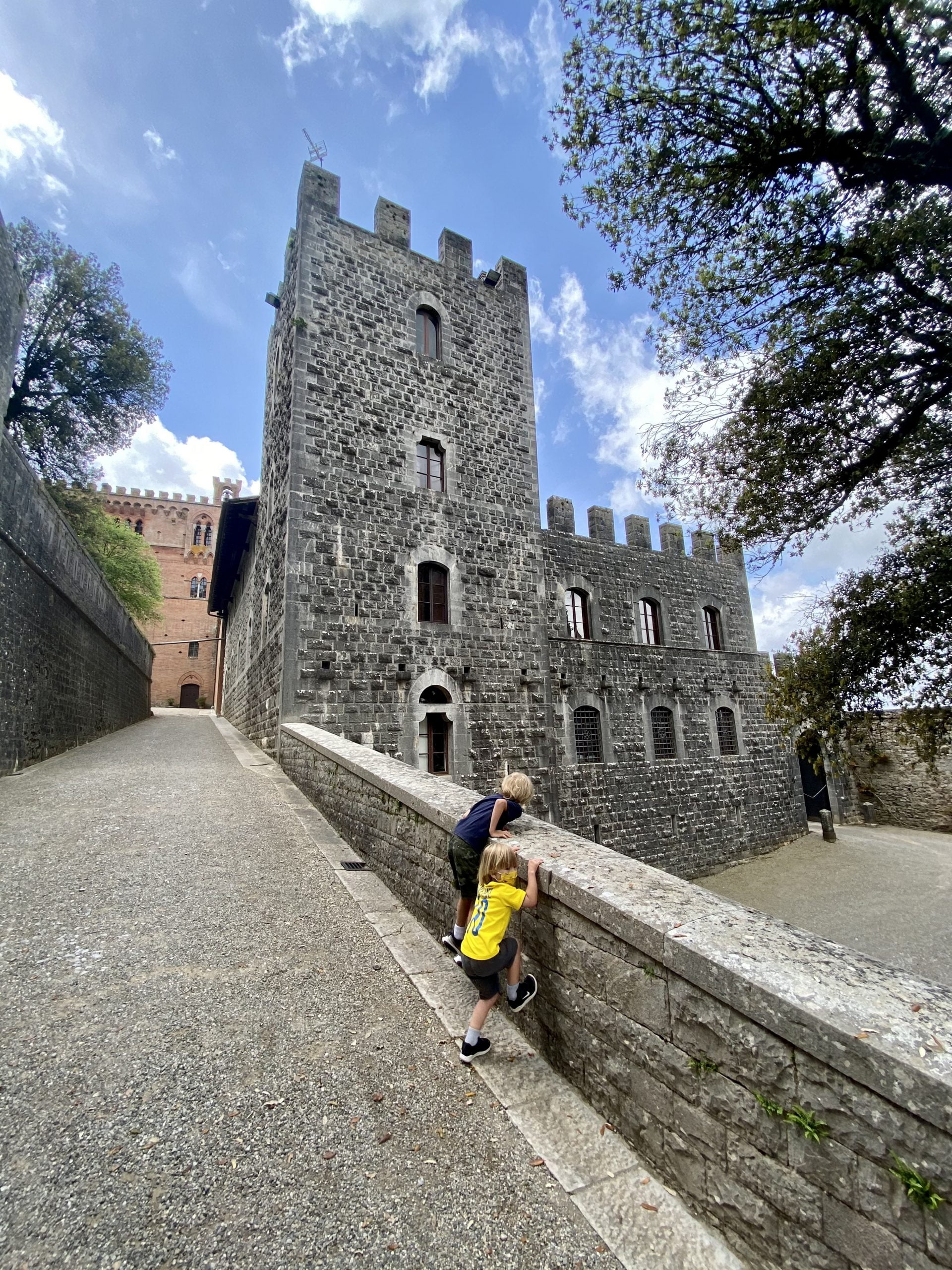 Boys looking at Brolio castle (Castello di Brolio) from a small wall